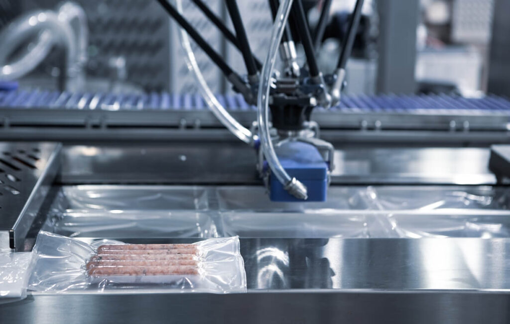 Automated thermoforming machine sealing plastic packaging on a production line.